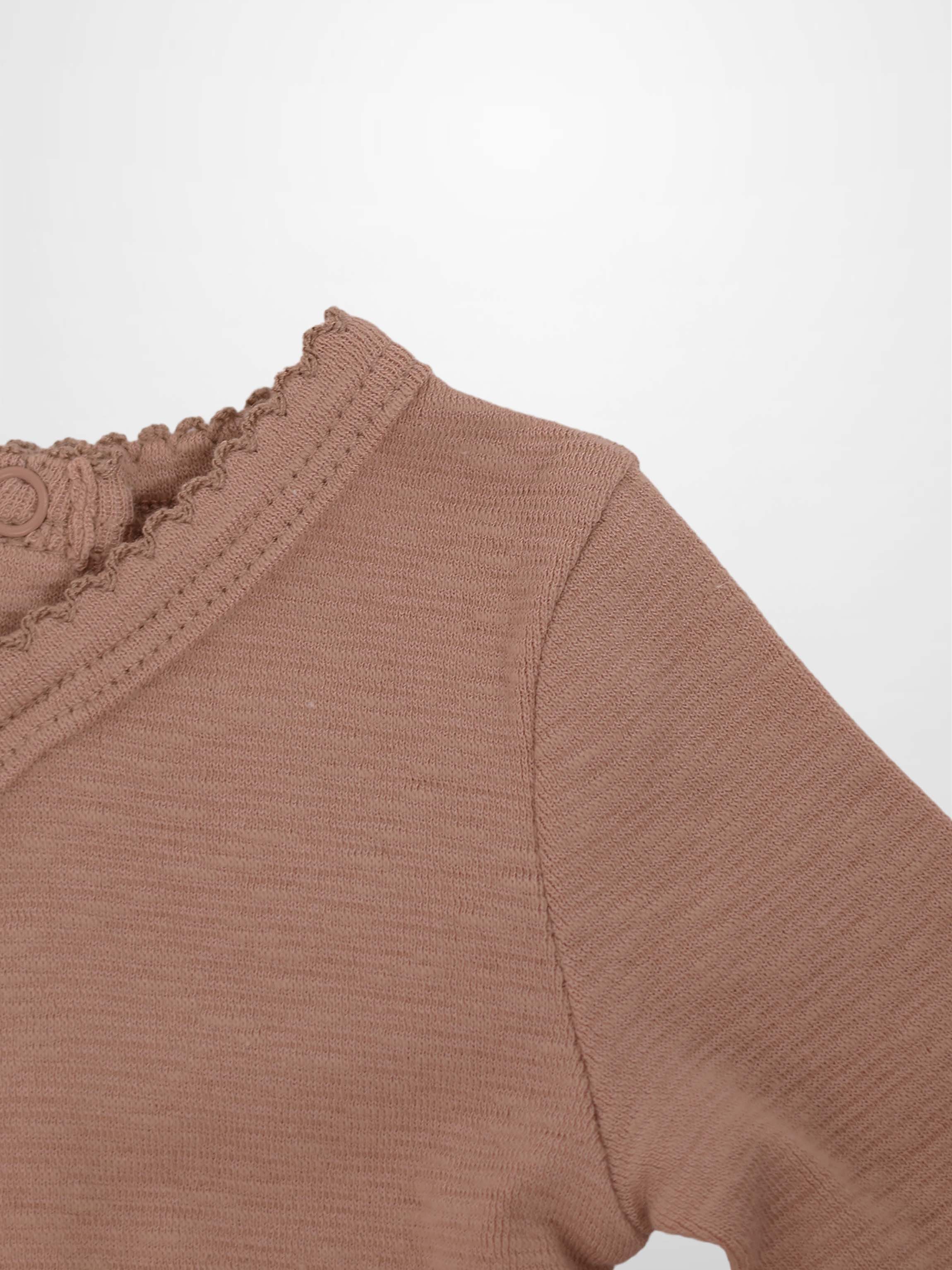 Dusty pink knit baby outfit close-up with scalloped neckline trim and loop button.
