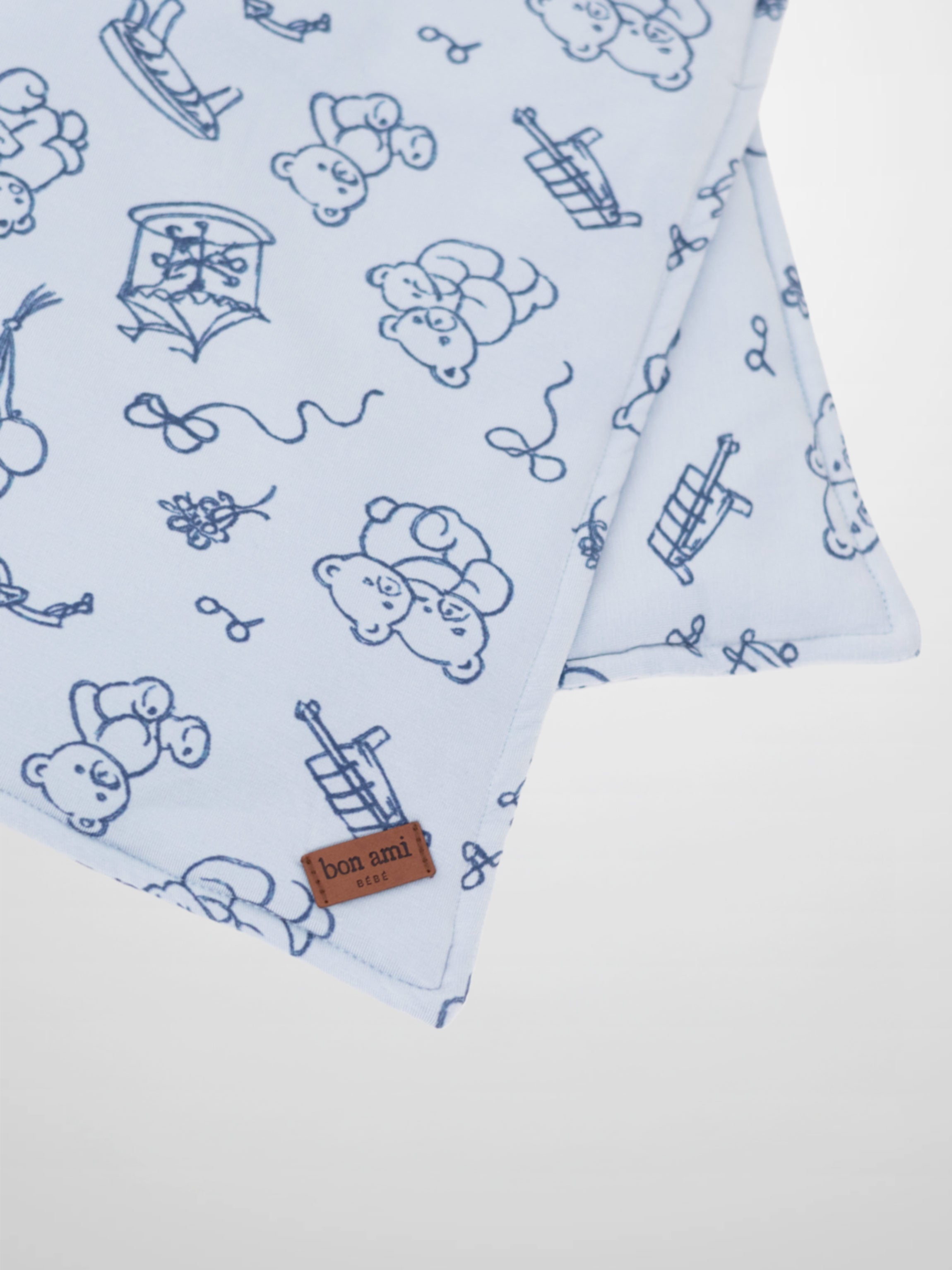 Light blue square lovey with dark blue storybook print of carousels, bears, balloons and rocking horses; Bon Ami tag.