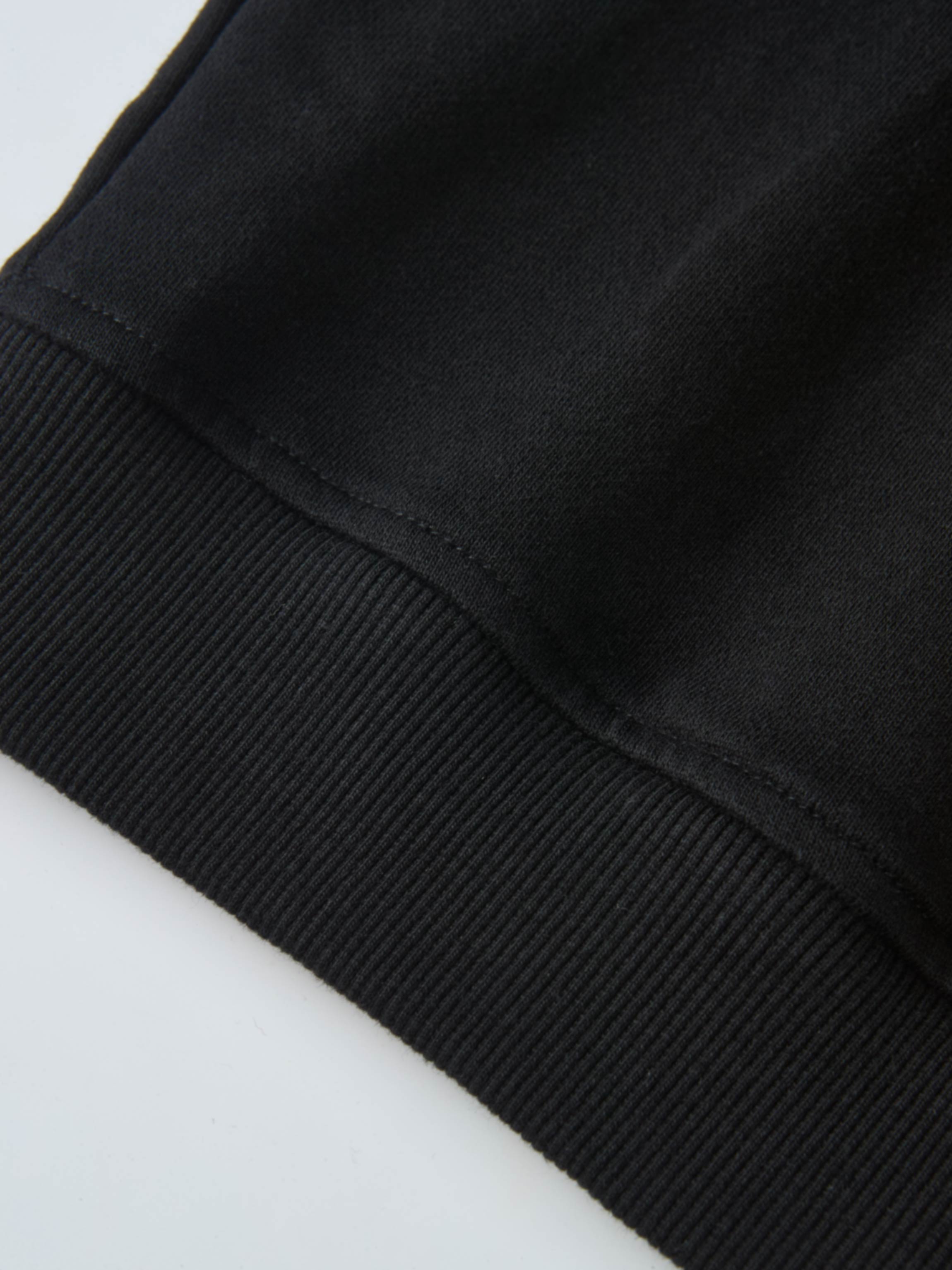 Collared Sweatshirt in black; close-up shows ribbed cuffs and smooth fabric.