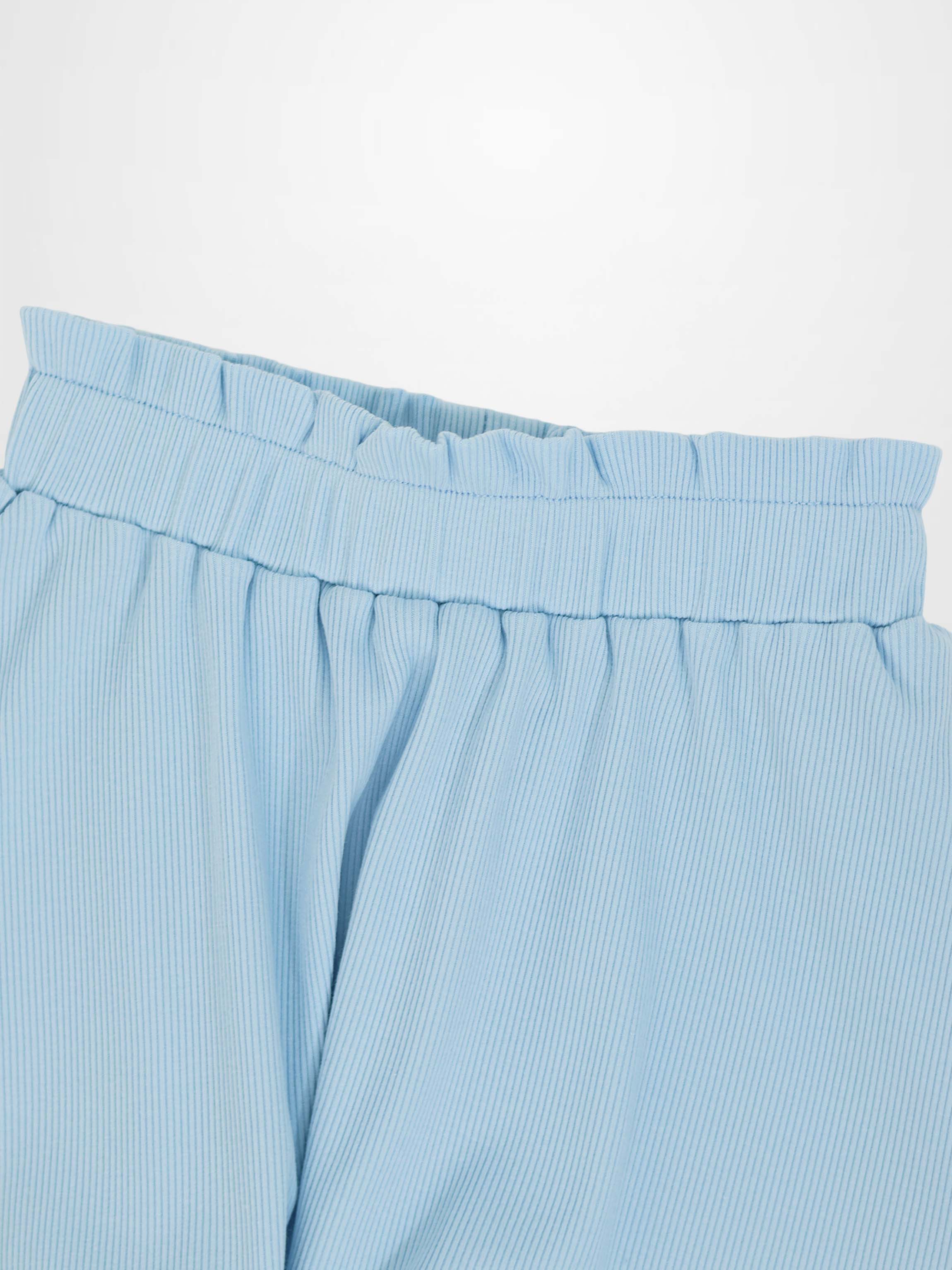 Close-up of light blue paper bag waist skirt with elasticized waistband and gathered fabric.