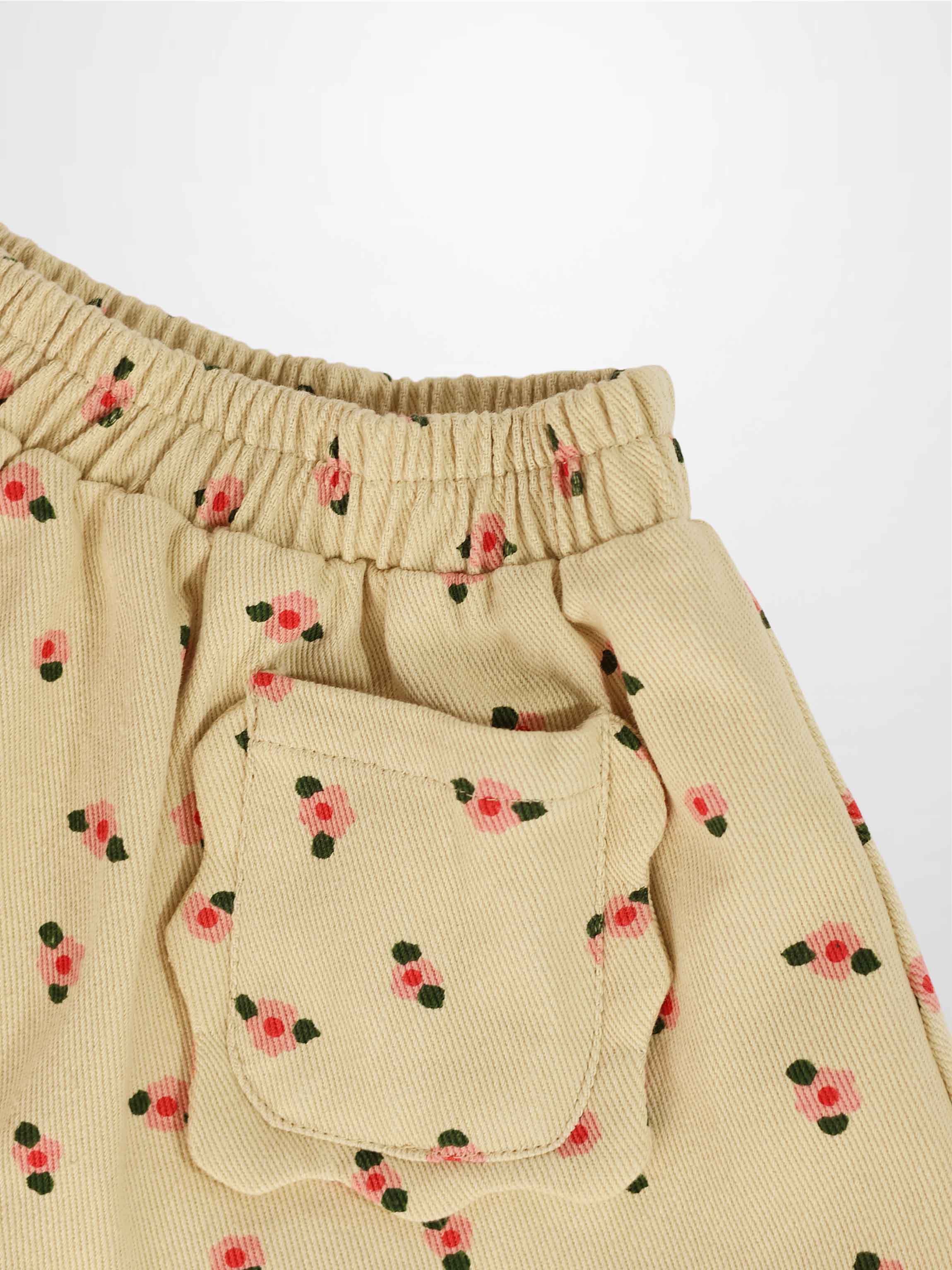 Tan floral skirt with elastic waistband, pink blossoms and green leaves, featuring a front pocket.