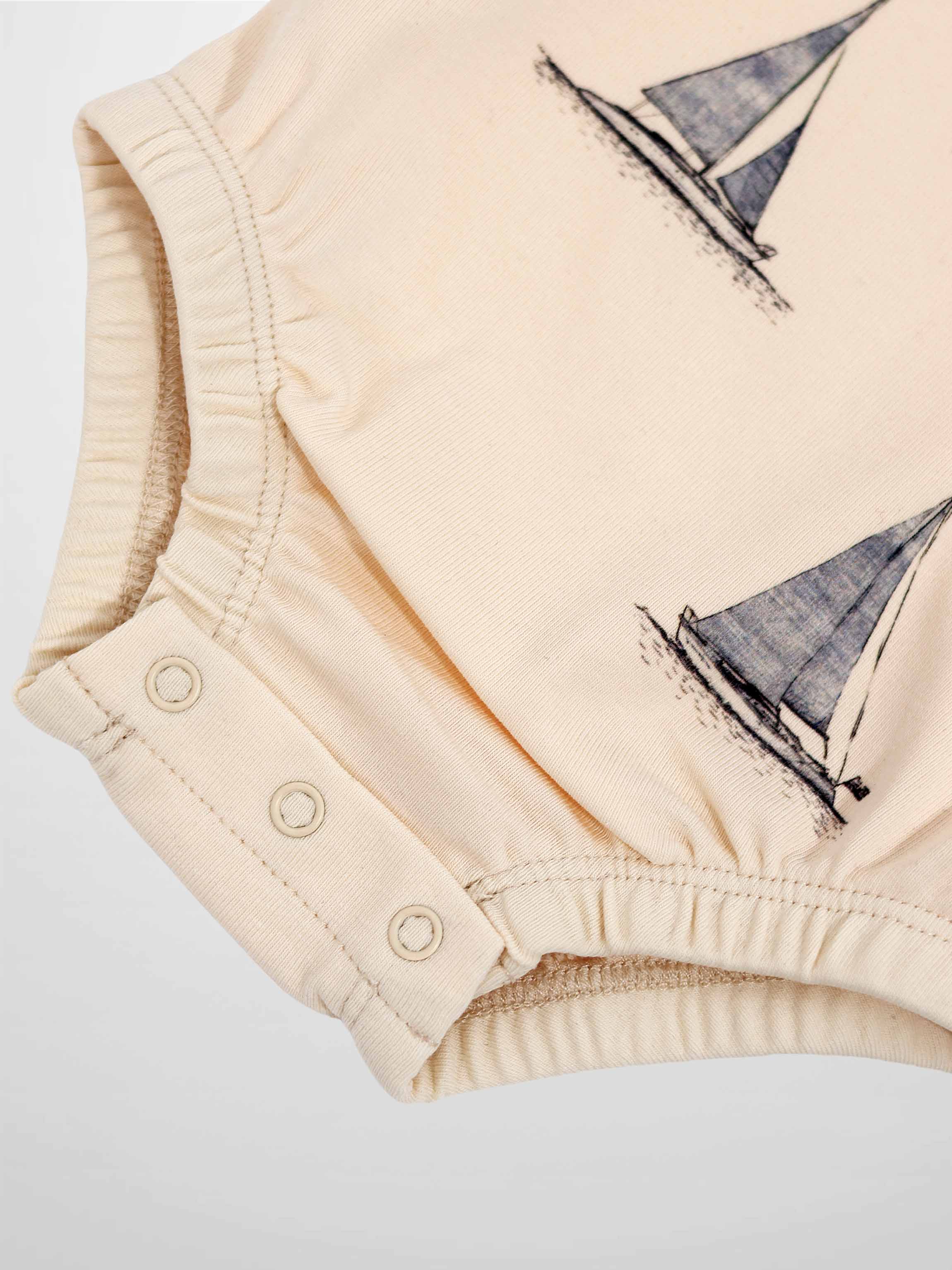 Sail Boat Romper in pale peach with sailboat print and snap closures at the bottom.