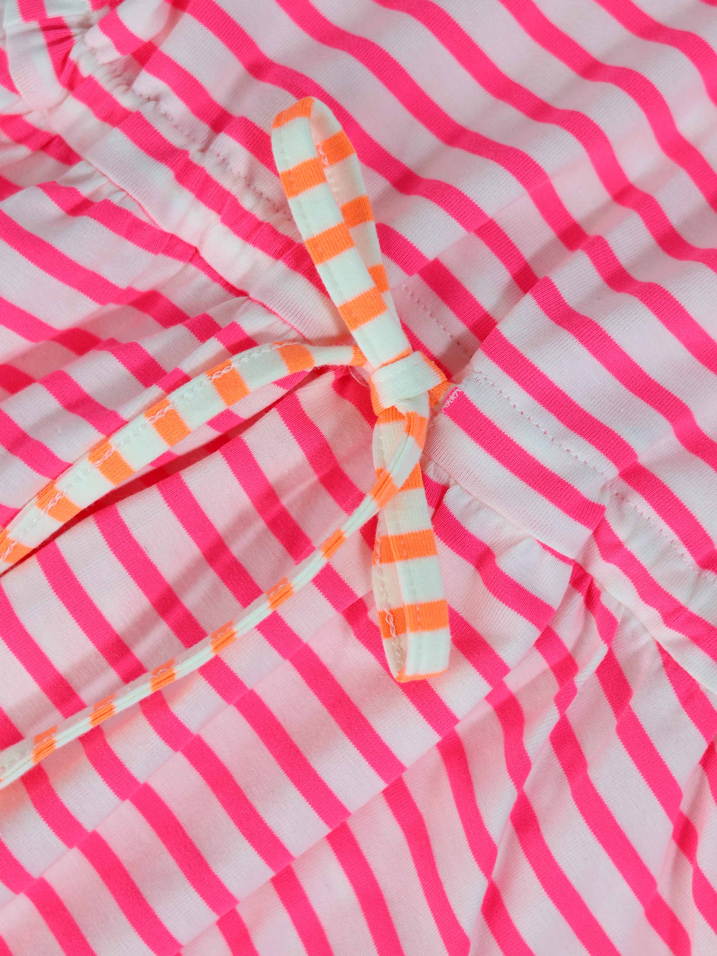 Neon pink striped dress with short sleeves and a white-and-orange striped waist bow.
