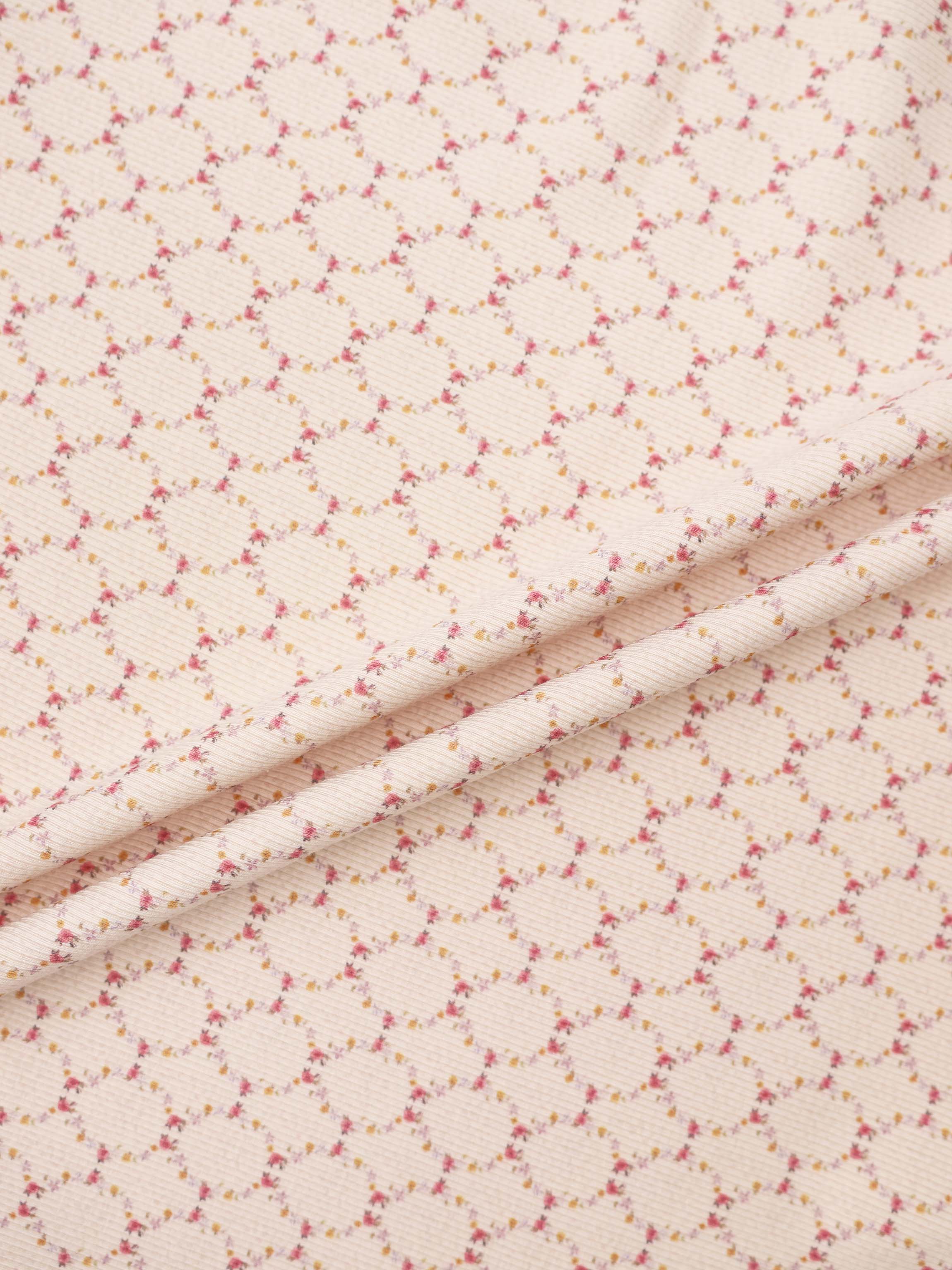 Floral Garland Layette Set fabric by Adee, peach background with tiny pink and yellow flowers.