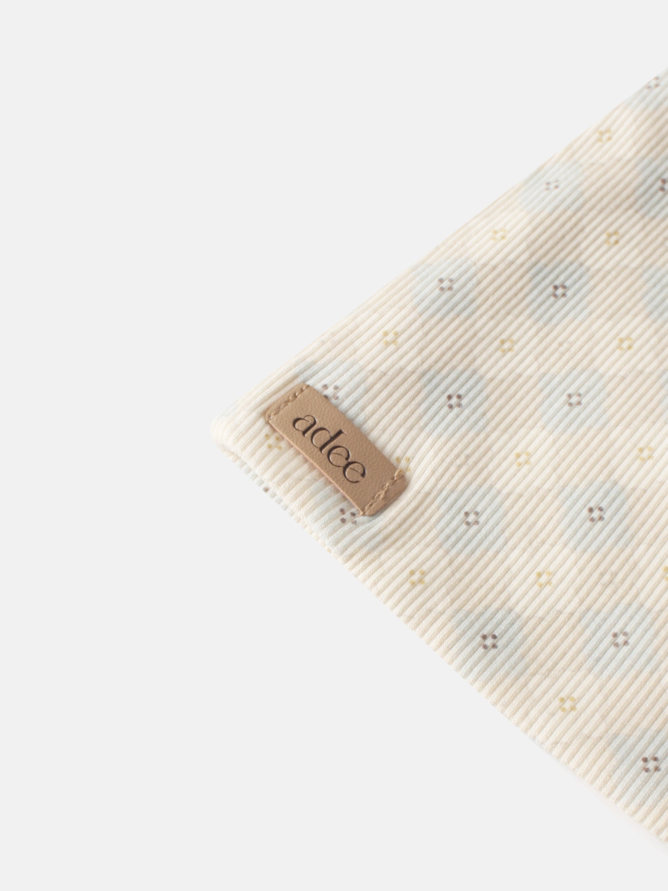 Little Button Blue layette set by Adee; beige striped fabric with tiny pastel cross motifs.