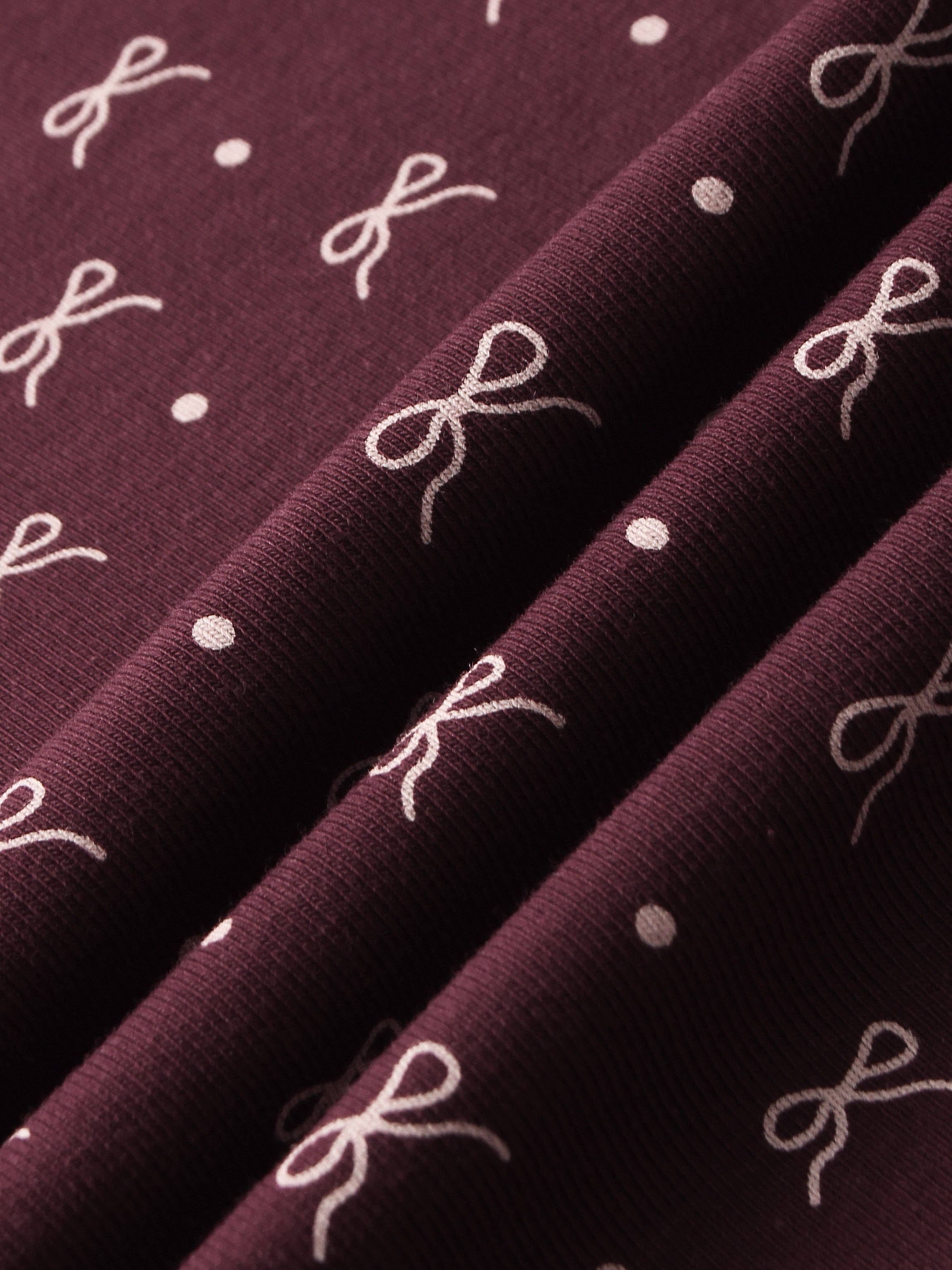 Girls hats in burgundy fabric with white bow motifs and dots.