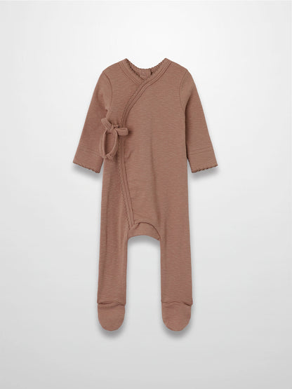 Dusty pink stretchy baby girl jumpsuit footie with side wrap crossover and scalloped trim.