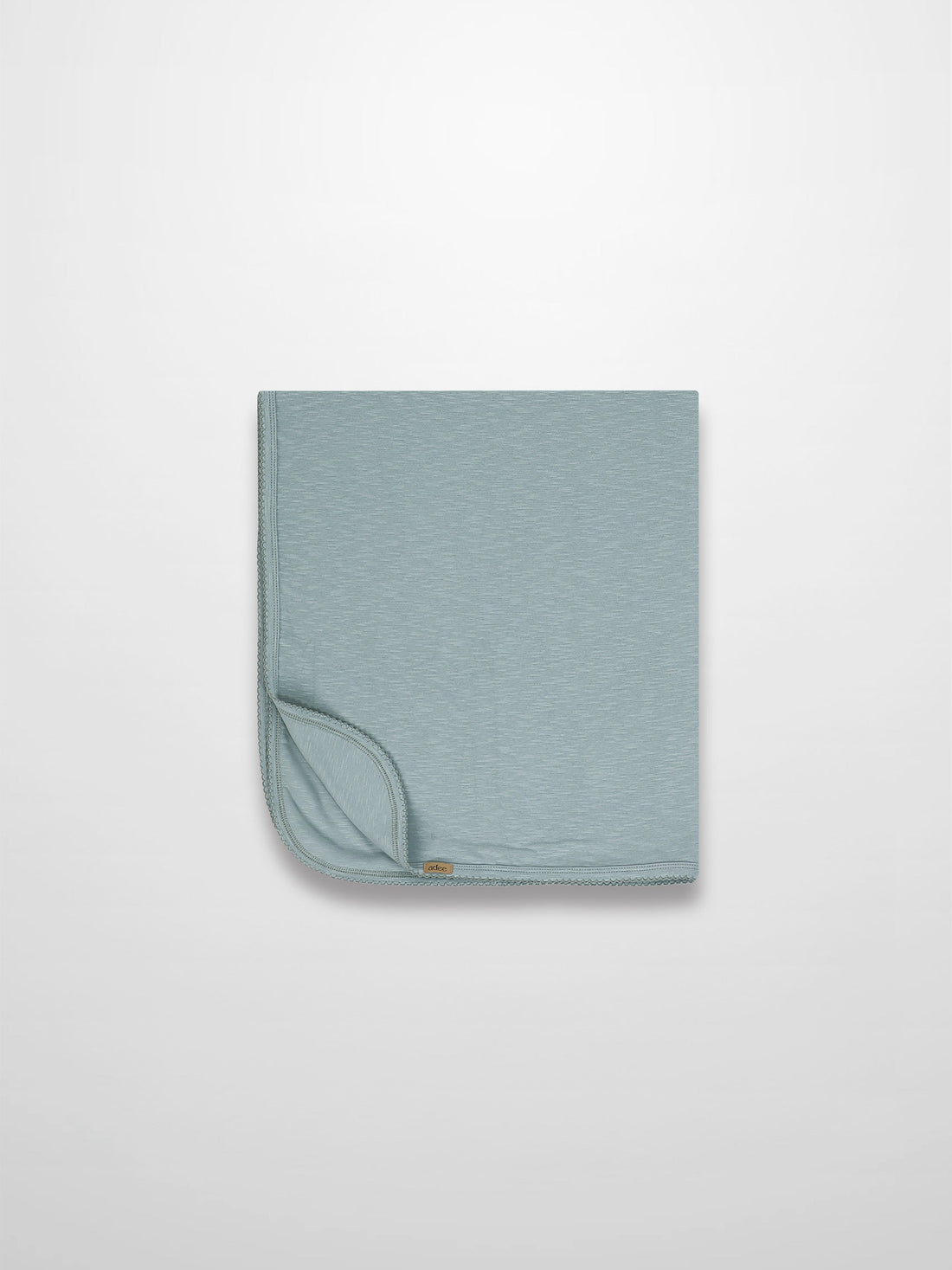 Blue Scalloped Baby Blanket in light blue with subtle texture and delicate scalloped trim, folded corner visible