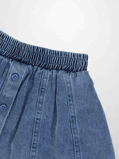 Paneled blue denim skirt with elastic waistband and front button placket.