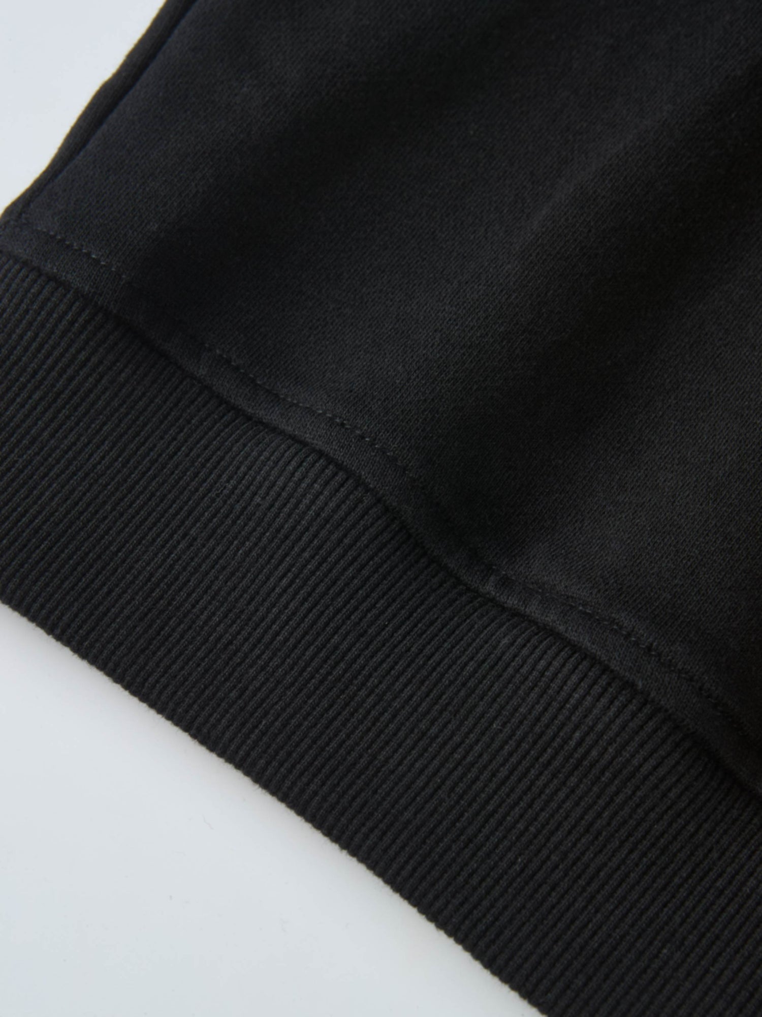 Collared Sweatshirt in black; close-up shows ribbed cuffs and smooth fabric.