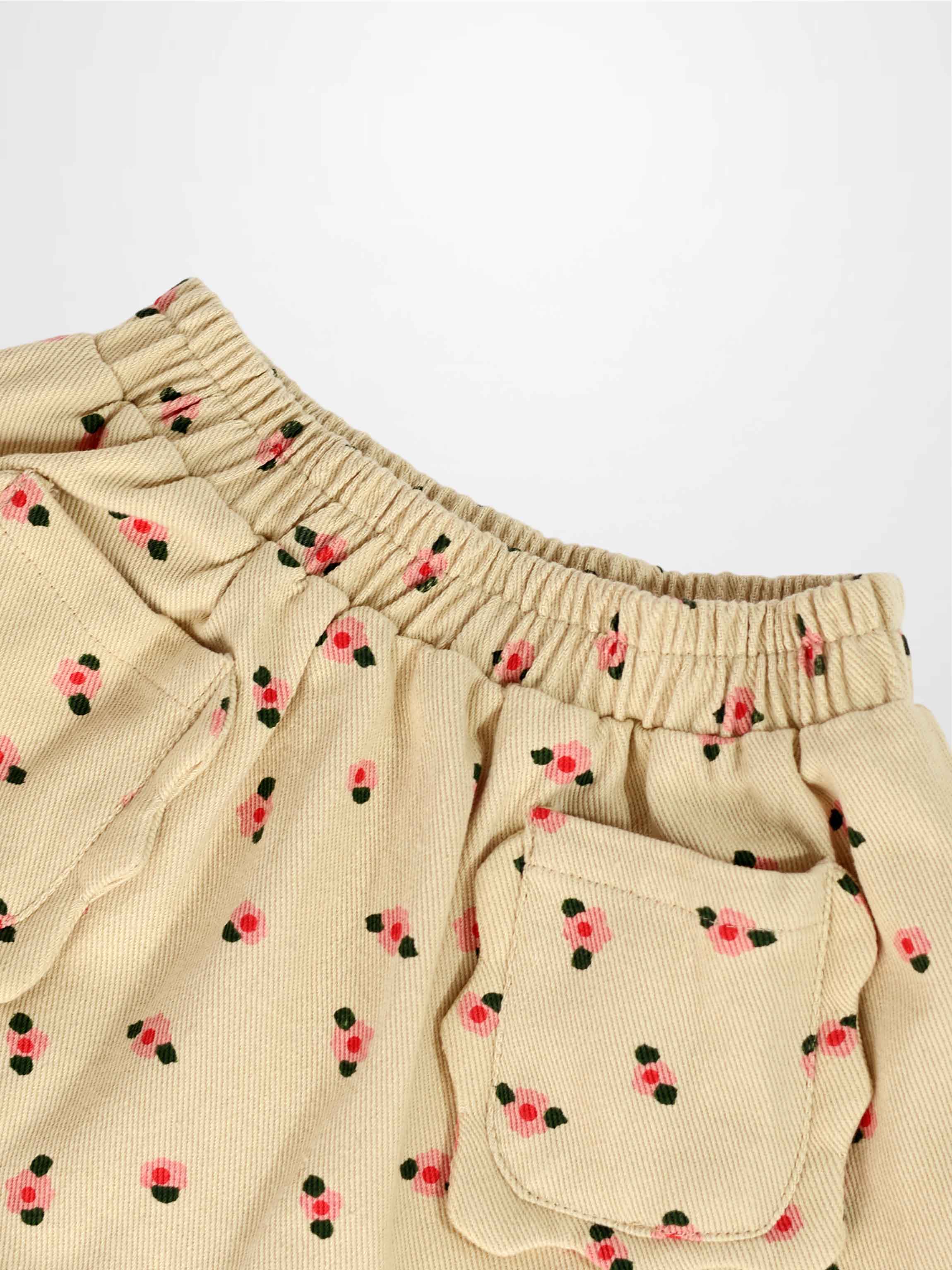 Tan floral skirt with pink blossoms and green leaves, featuring an elastic waistband and front pocket.