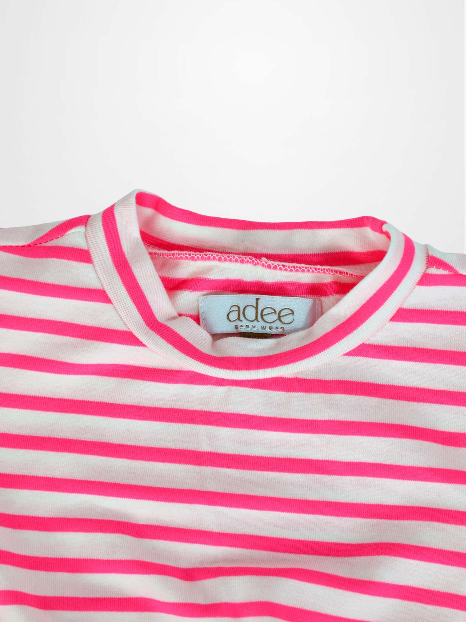 Neon pink and white striped short-sleeve dress neckline close-up with visible brand tag.