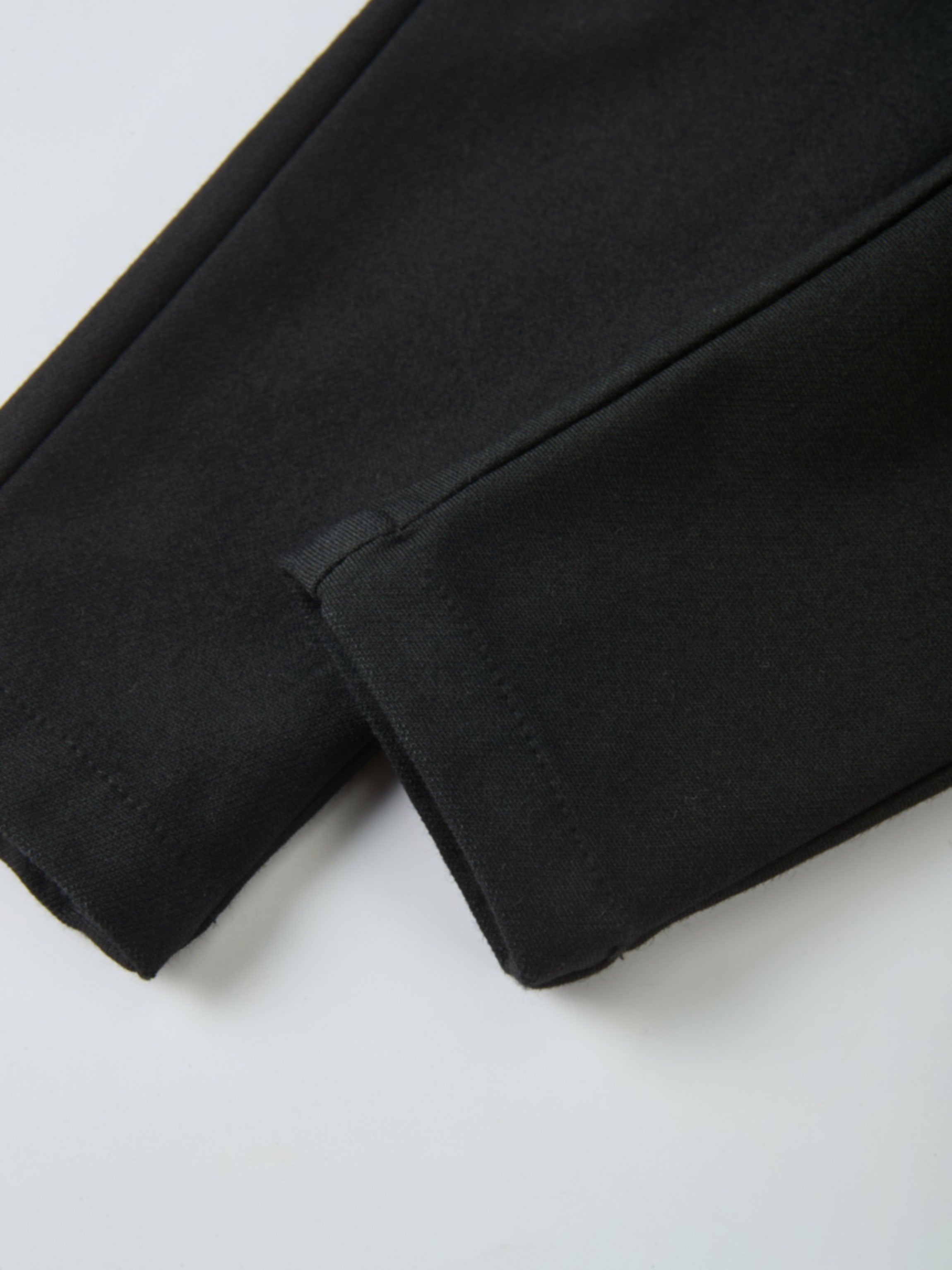 Denim overalls by Adee in black, unisex; close-up of fabric and seam.
