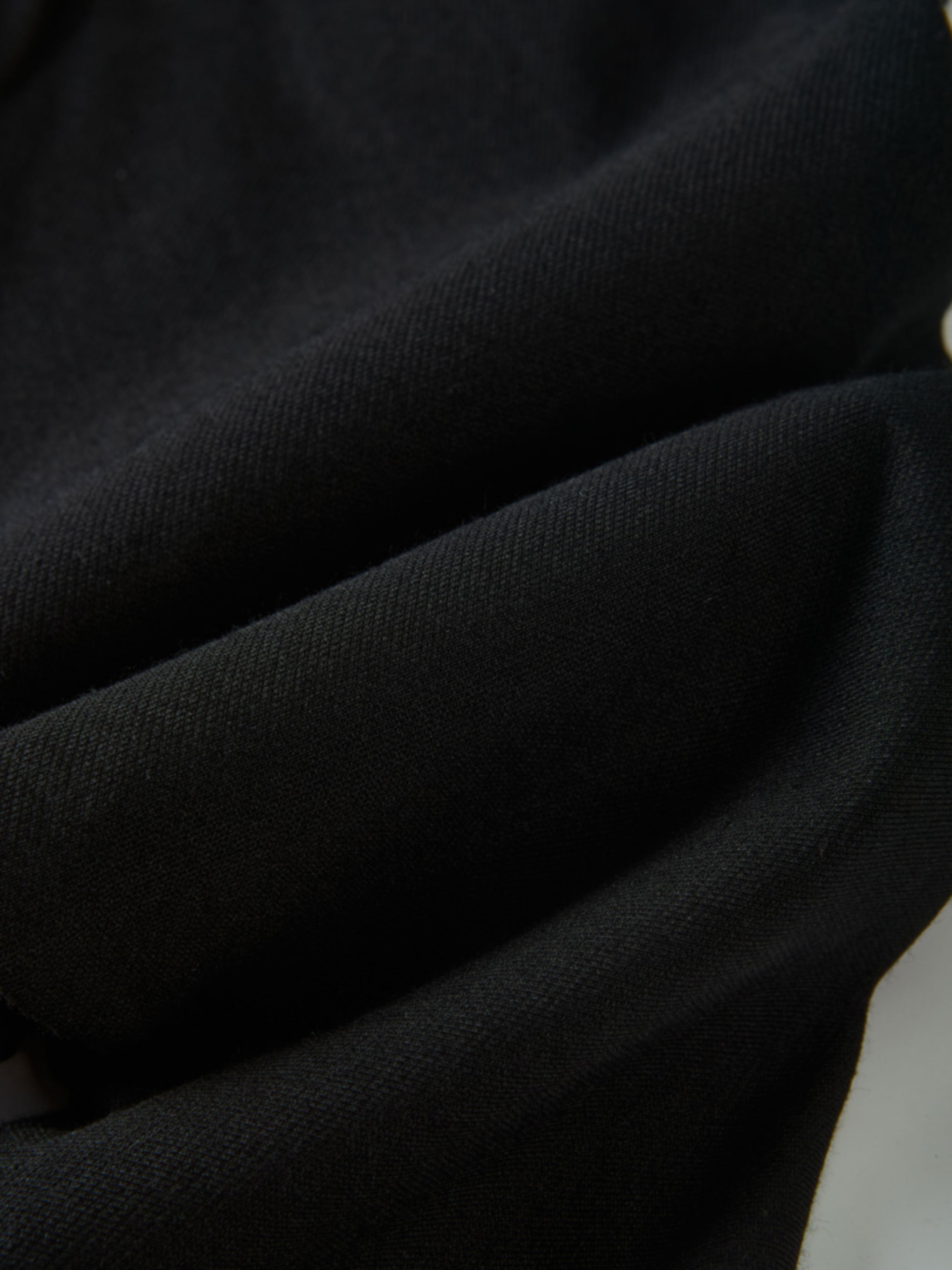 Denim overalls in black by Adee; close-up of textured fabric with gold button detail and visible stitching.