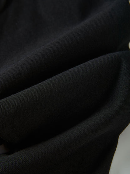 Denim overalls in black by Adee; close-up of textured fabric with gold button detail and visible stitching.