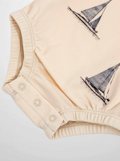 Sail Boat Romper in pale peach with sailboat print and snap closures at the bottom.