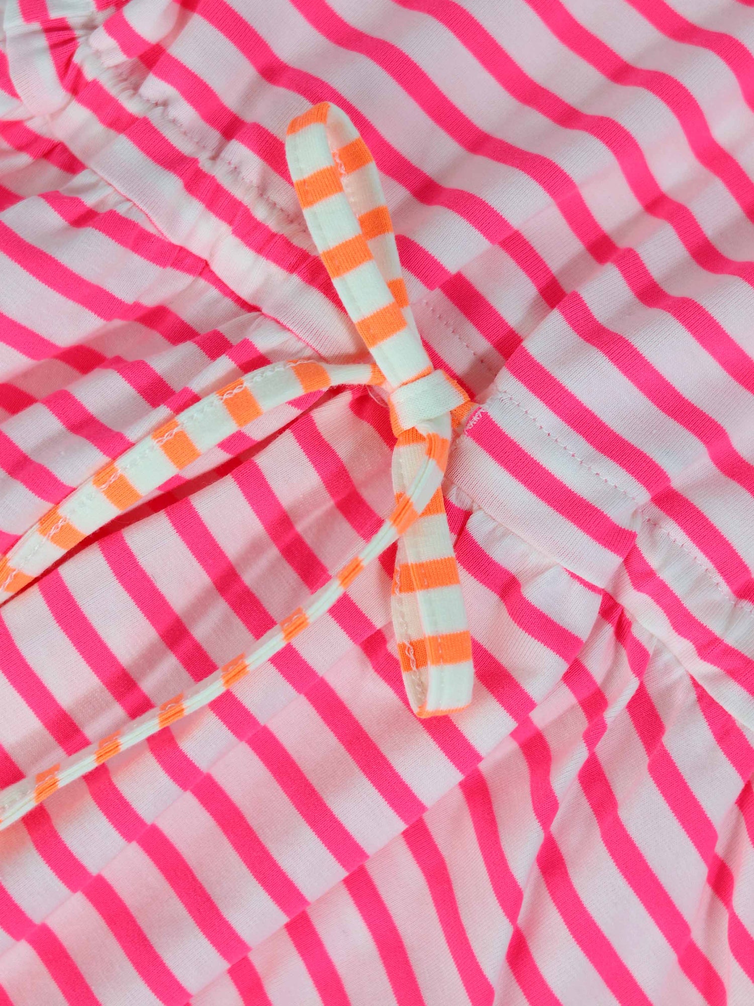 Neon pink striped dress with short sleeves and a white-and-orange striped waist bow.