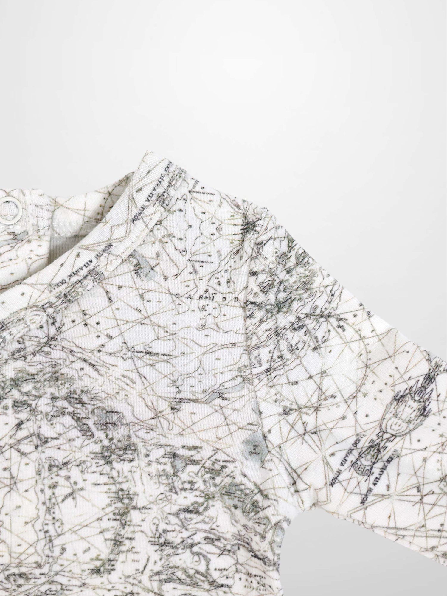 Map Stretchy baby boy jumpsuit footie with off-white fabric and sage-green map lines and compass markers.