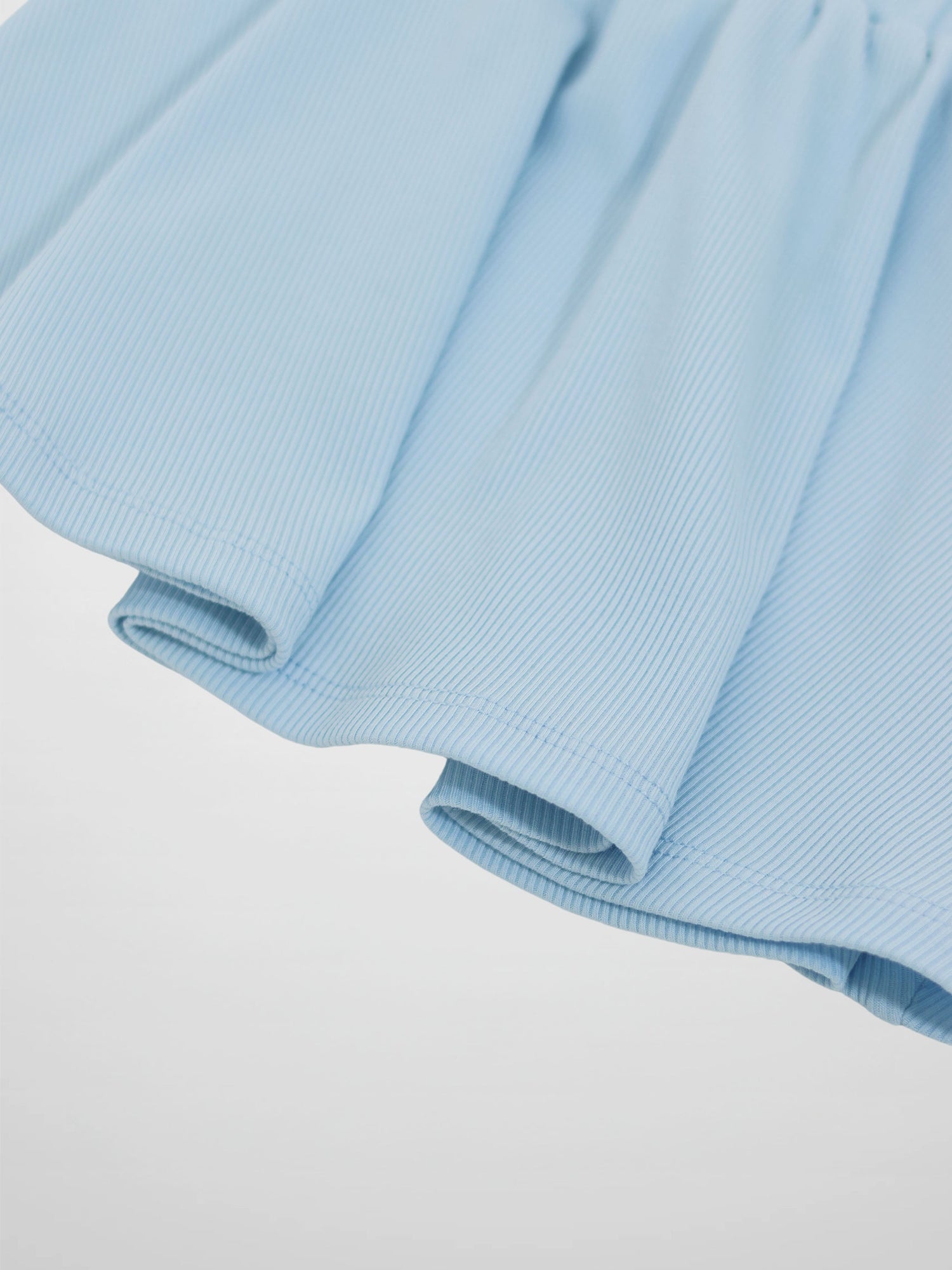 Light blue paper bag waist skirt with ribbed fabric and soft folds.