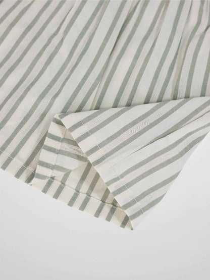 Green striped dress fabric close-up with folded sleeve edge.