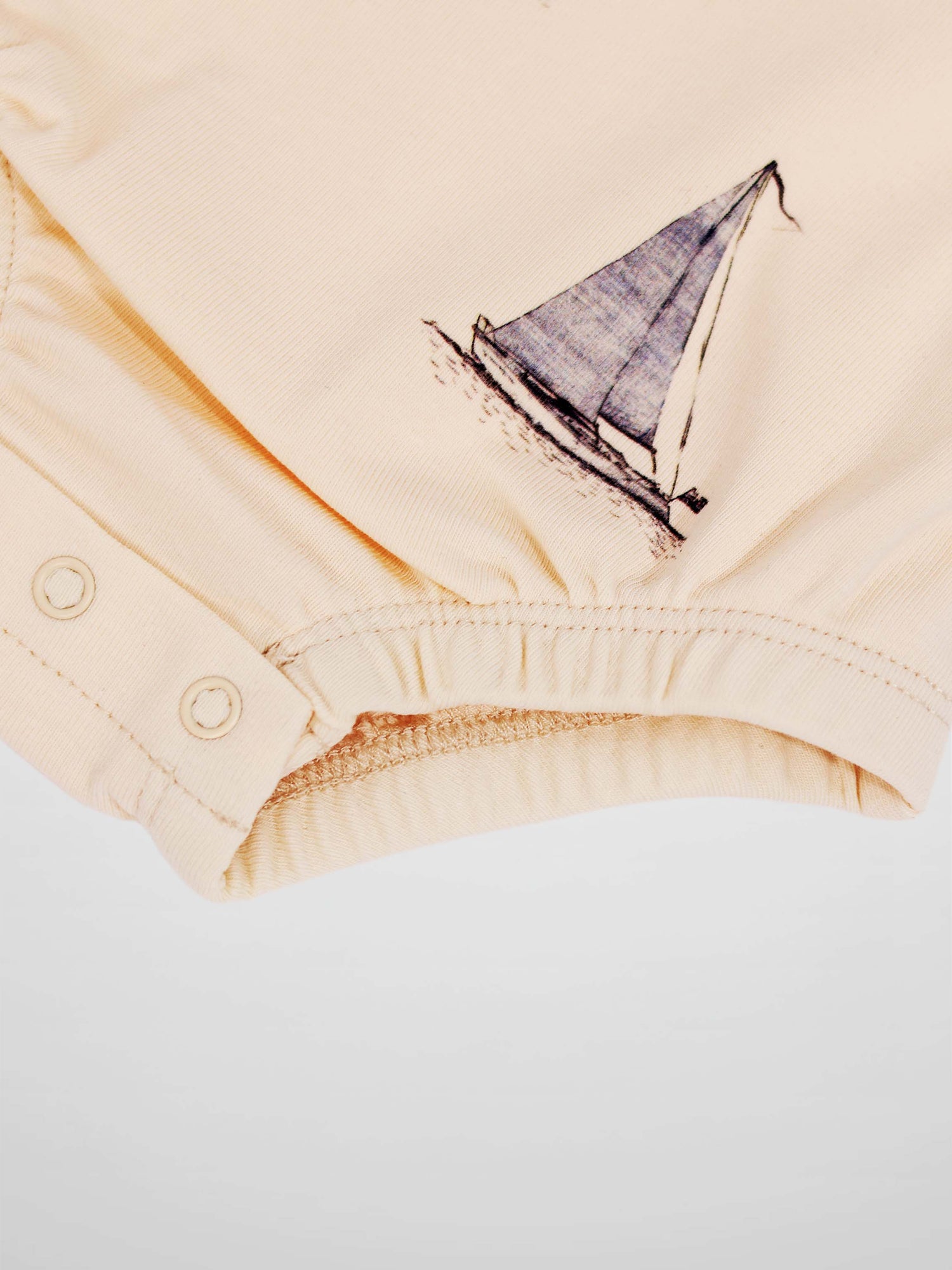 Beige Sail Boat Romper fabric with a blue sailboat illustration and snap-button leg opening.