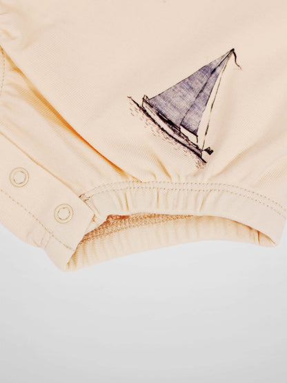 Beige Sail Boat Romper fabric with a blue sailboat illustration and snap-button leg opening.