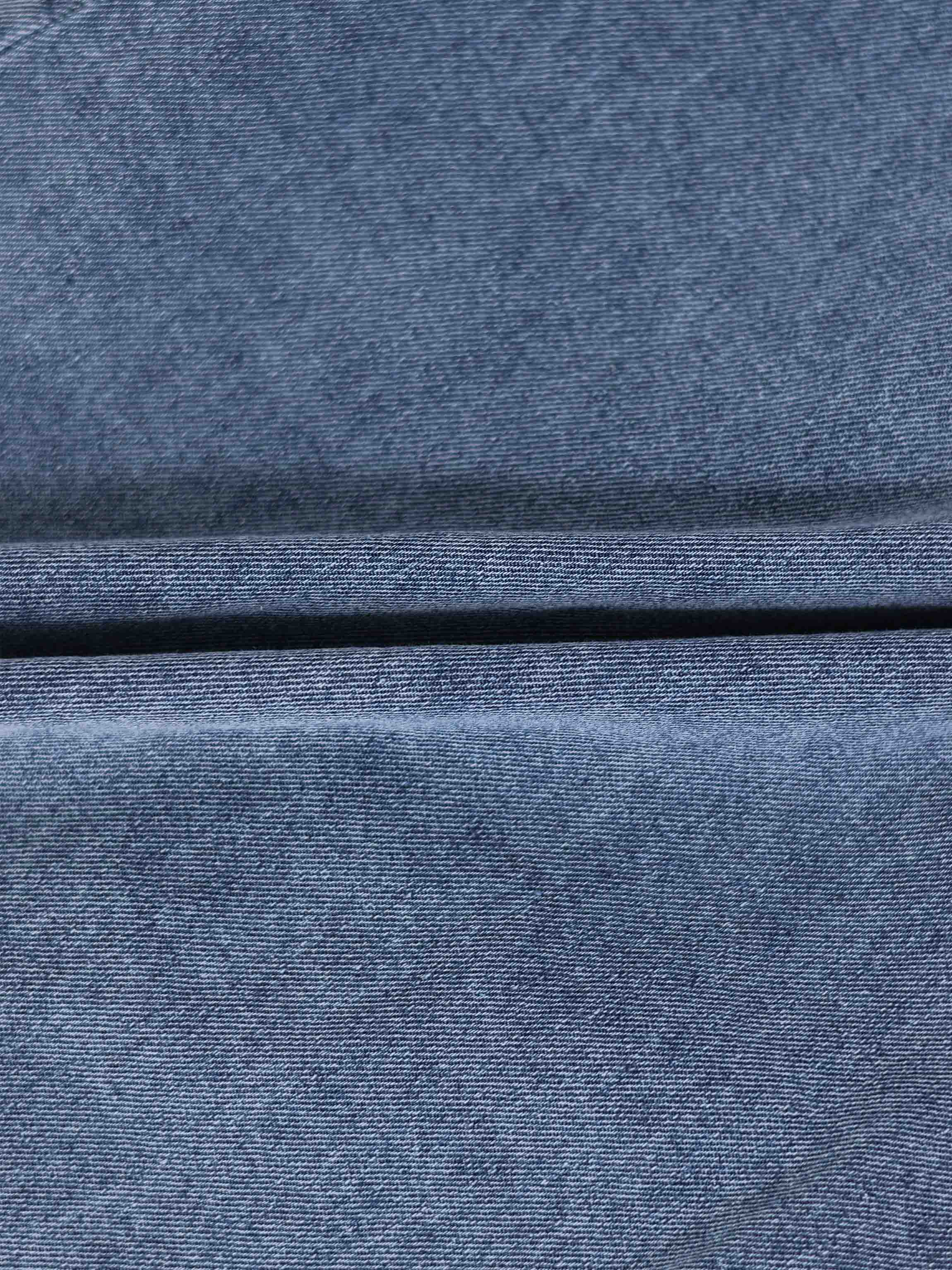 Blue denim fabric close-up showing twill weave and seam.