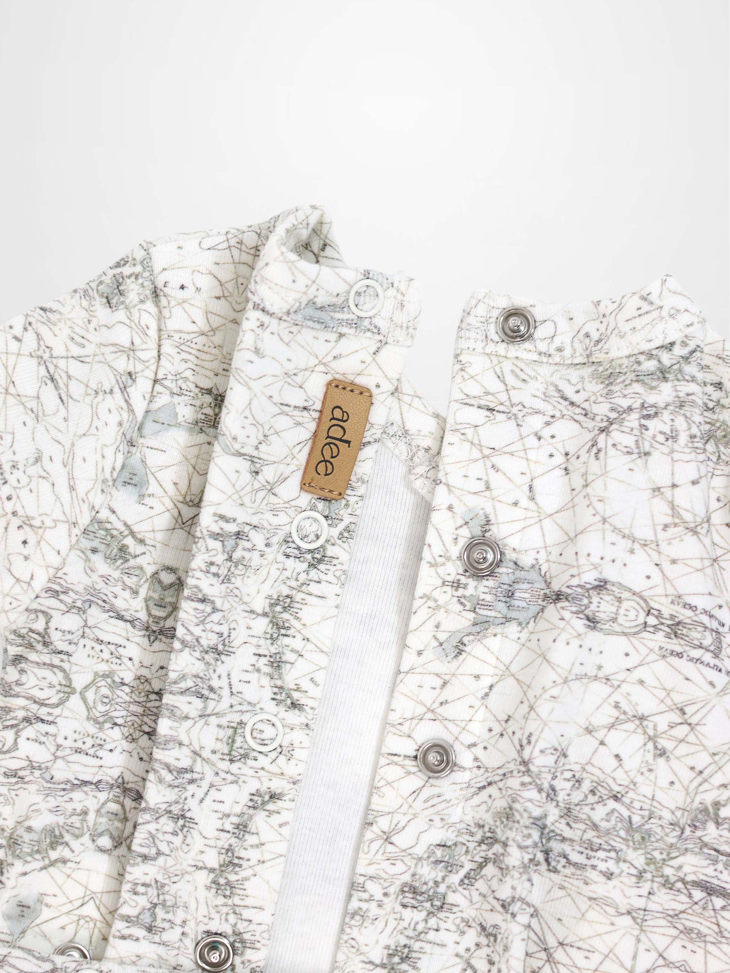 Map Stretchy baby jumpsuit footie in off-white with sage map print, compass markers, and crossover detail.