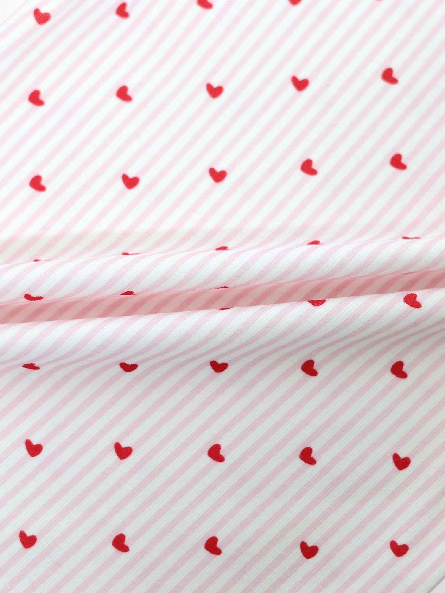 Light pink and white striped fabric with small red hearts for a baby jumpsuit footie.