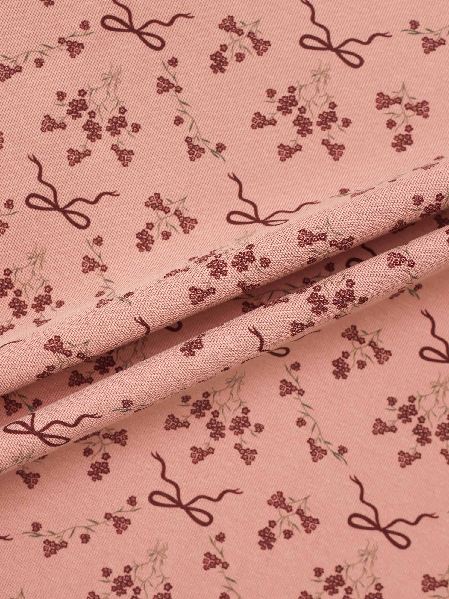 Bow Bouquet Layette Set fabric for girls; pink with burgundy floral clusters and ribbon bow motifs.