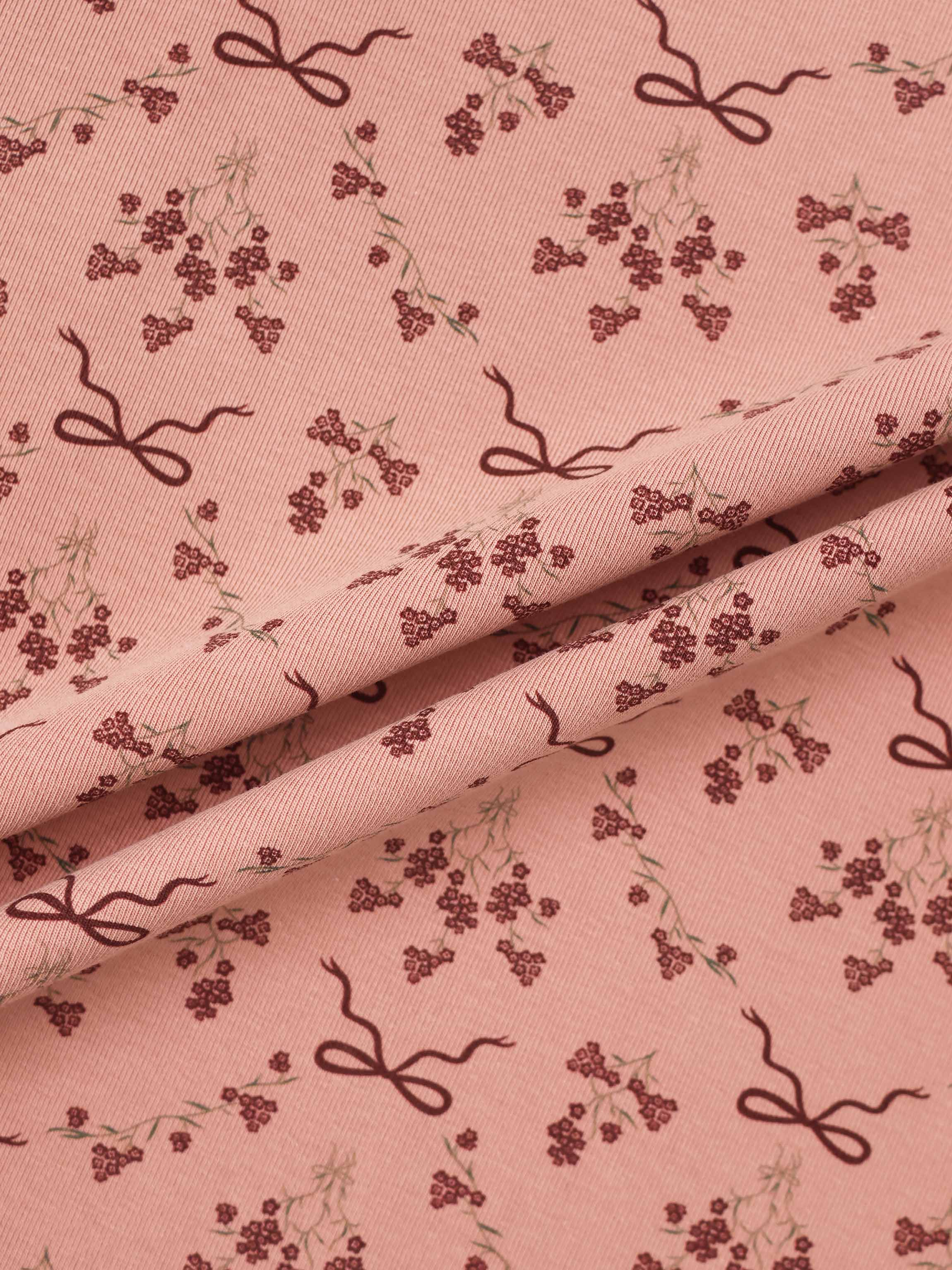 Bow Bouquet Layette Set fabric for girls; pink with burgundy floral clusters and ribbon bow motifs.