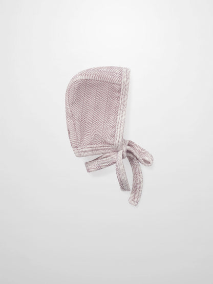 Heritage Herringbone Red layette bonnet by Adee with tied straps in pink-red herringbone fabric.