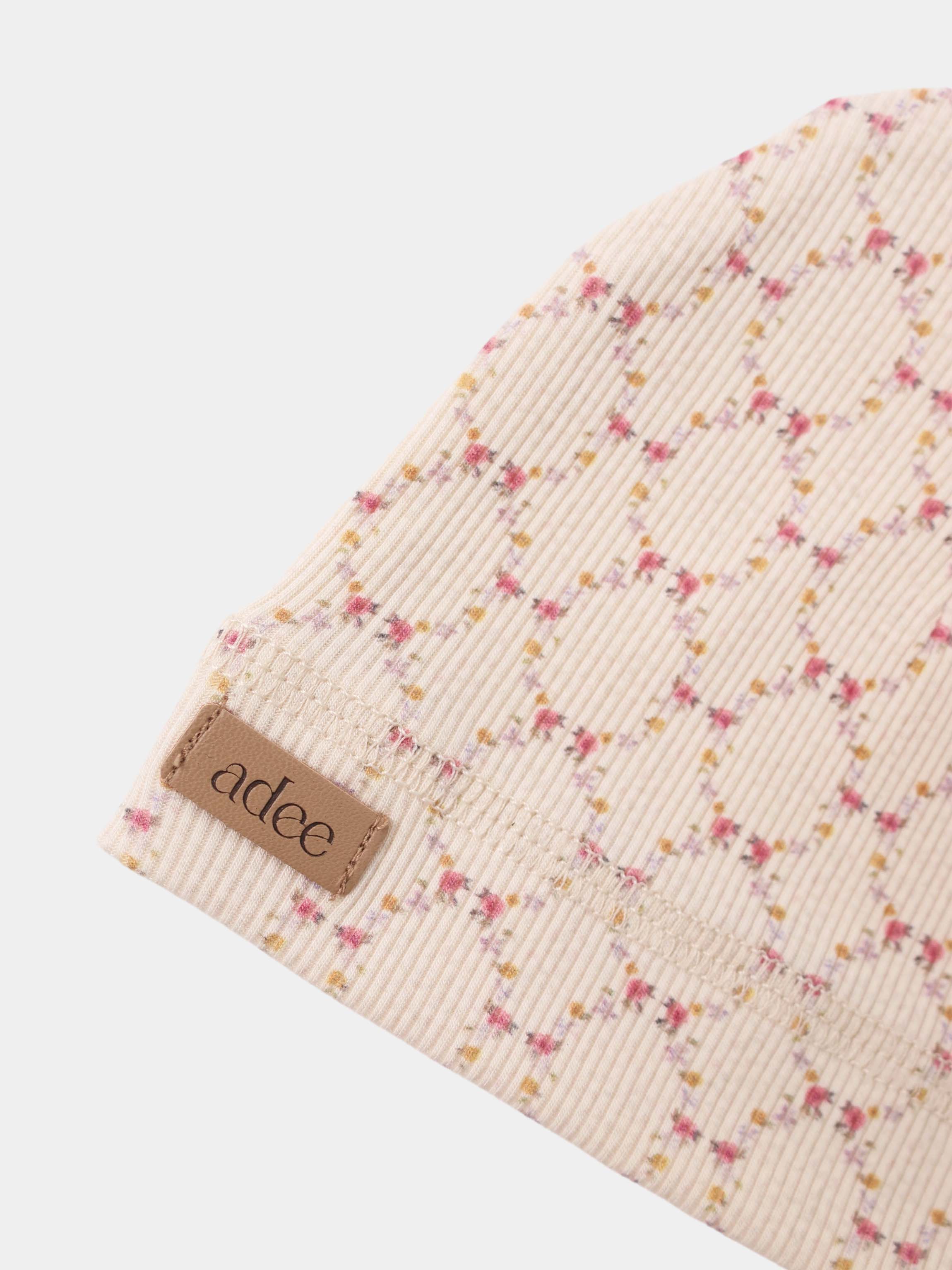 Floral Garland layette set by Adee on cream ribbed fabric with tiny pink and yellow flowers