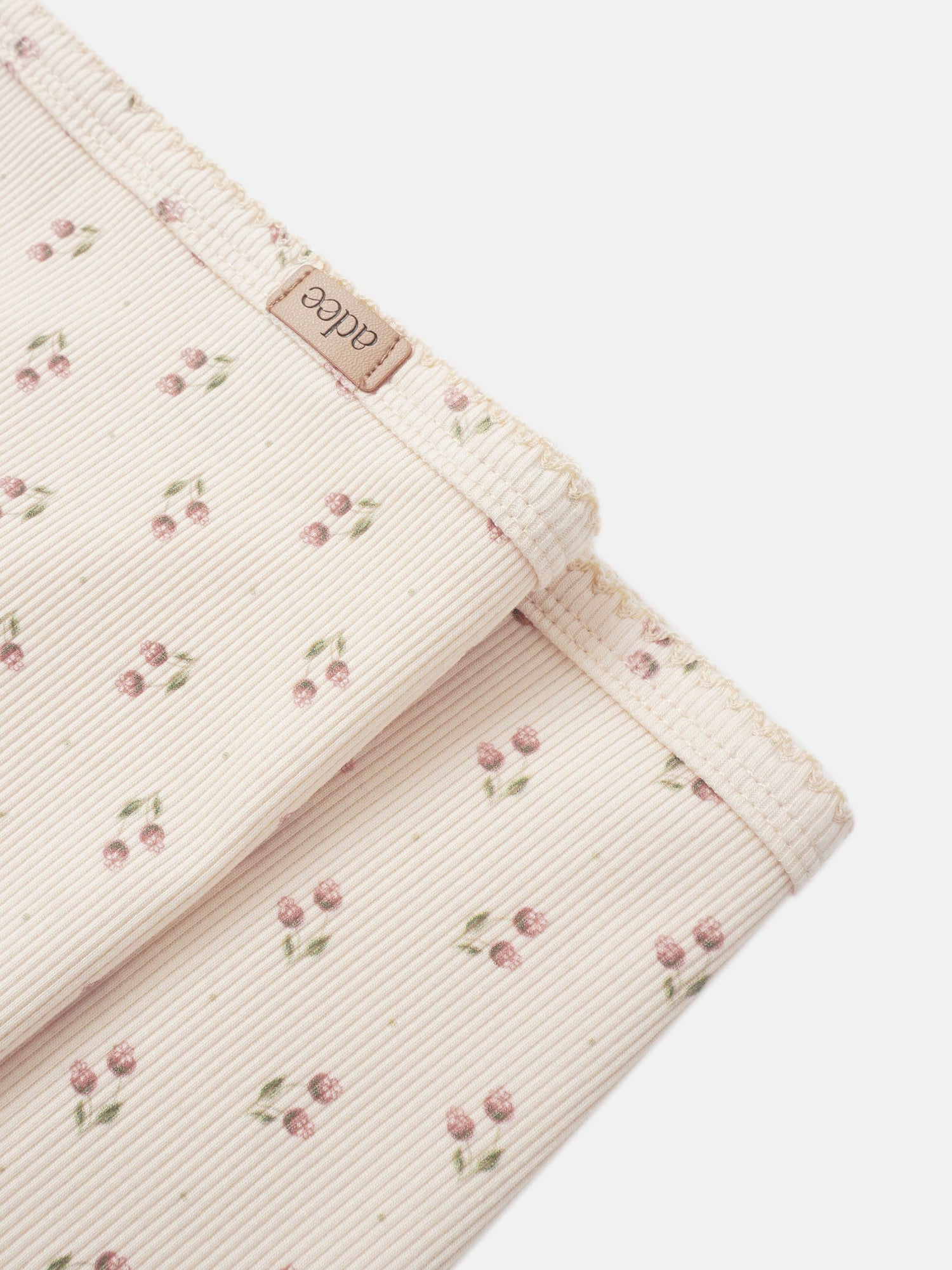 Adee Tiny Tulip layette set for girls; pale pink ribbed corduroy with tiny cherry blossoms, brand tag visible.