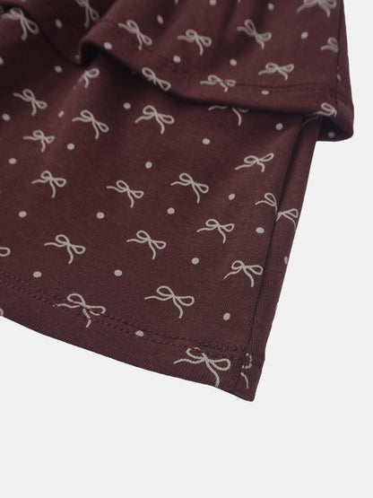 Burgundy bow-patterned girls skirt fabric close-up showing white bows and dots