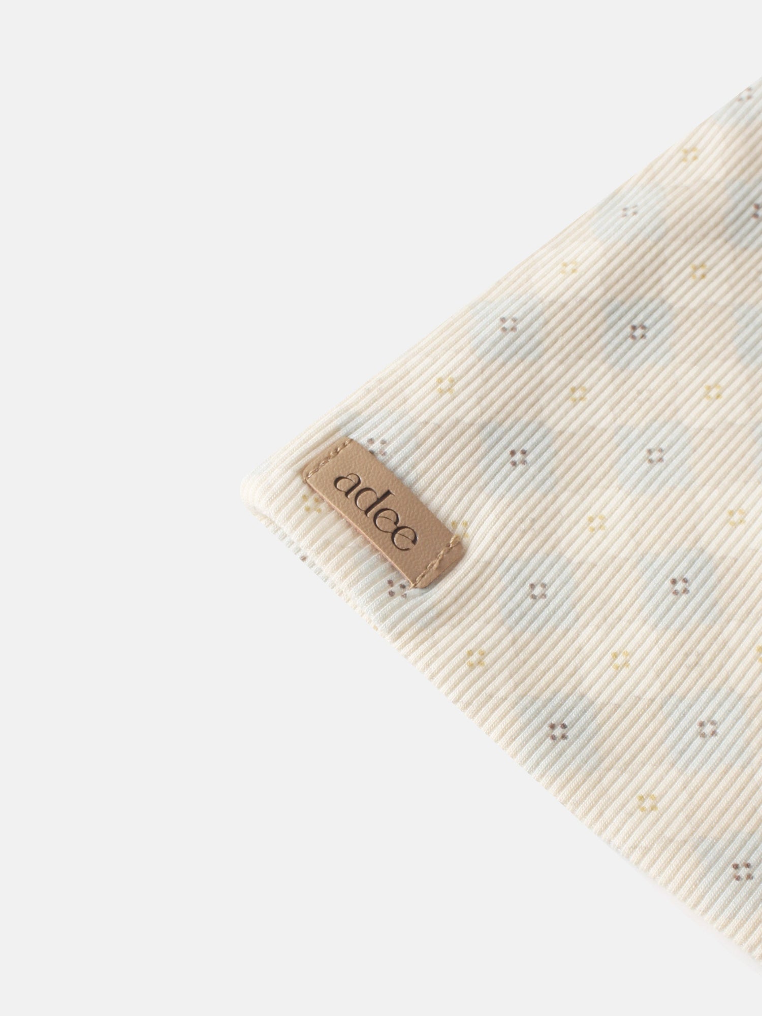 Little Button Blue layette set by Adee; beige striped fabric with tiny pastel cross motifs.