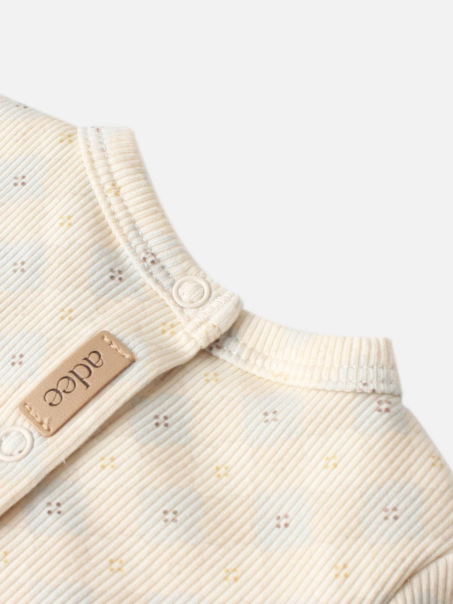 Little Button Blue layette set by Adee; cream ribbed cotton fabric with tiny embroidered specks and white button.