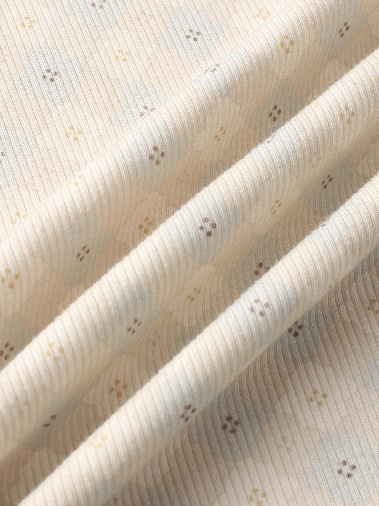 Little Button Blue layette fabric by Adee; cream knit with tiny brown and yellow dotted clusters.