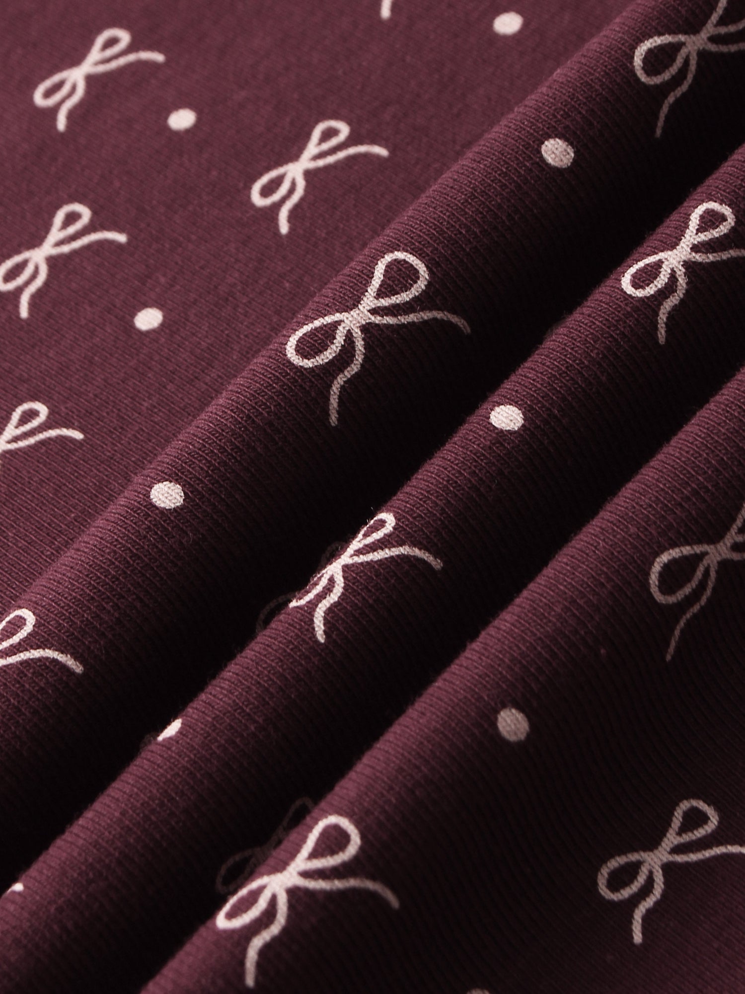 Girls hats in burgundy fabric with white bow motifs and dots.